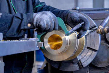 The specialist measures the manufactured part fixed in the lathe. Soft focus - obrazy, fototapety, plakaty