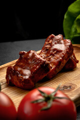 fried ribs in sauce served on a board, on a dark background
