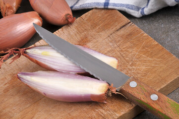 Échalote coupée en deux avec un couteau sur une planche à découper en gros plan