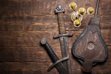 Blacksmith bellows and swords on the wooden flat lay workbench background.