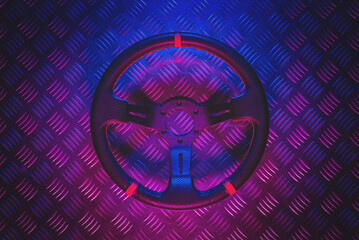 A sport car steering wheel in the neon lights flat lay background. Car tuning accessory.
