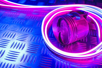 Car engine piston in the neon lights close up background with copy space.