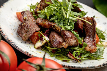 salad of steak, arugula and cherry tomatoes, on a dark background