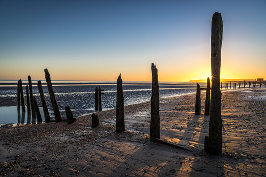 Sunset over the groynes on the beach at Rye Harbour, East Sussex, England