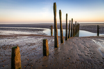 Sunset on groynes on the beach at Rye Harbour, East Sussex, England