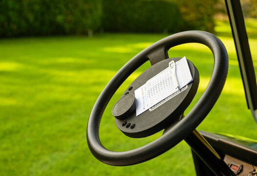 The Player Keeps The Score On The Golf Course. The Score Placed On The Steering Wheel Of The Golf Car. In The Background The Fairway