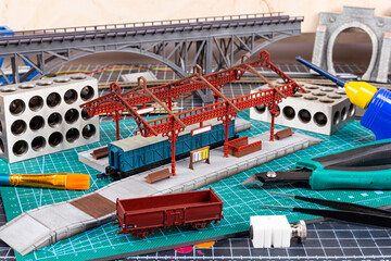 construction of model railroad layout. workbench with model railway train station bridge tracks and...