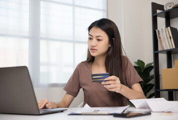 Fototapeta premium Stressed young asian woman holding credit card in put the payment on laptop but Not enough money on credit card to pay
