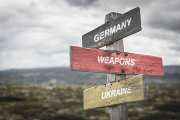 germany weapons ukraine text quote on german flag painted on wooden signpost outdoors in nature. To simulate the conflict in ukraine, europe.