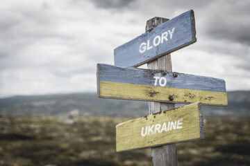 glory to ukraine text quote on wooden signpost outdoors, written on the ukranian flag.