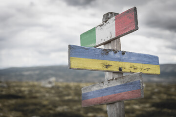 italy ukraine russia flag on wooden signpost outdoors in nature. Conflict in ukraine concept.
