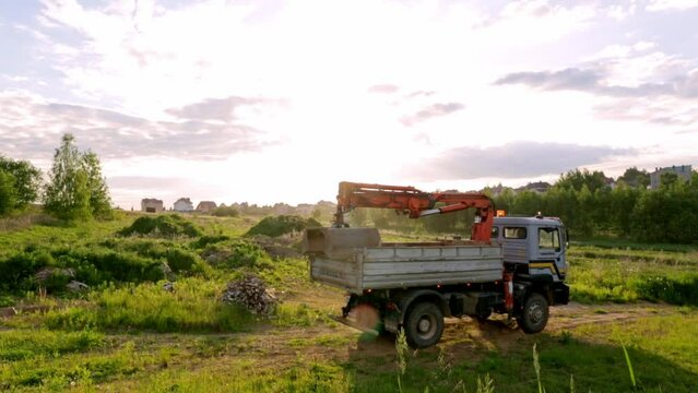 Dump truck with a bucket manipulator is unload the sand. Transport for a delivery of natural resources. Construction side. Building plot of privat property. Transportation. 