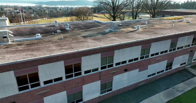 Public school building in USA. American flag. Classroom view with aerial shot. Bare trees, no leaves.