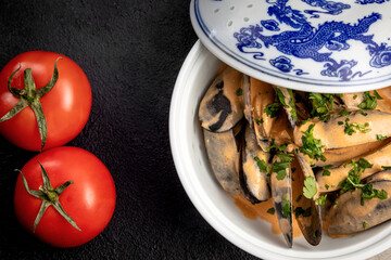 mussels in sauce in a ceramic dish on a dark decorated background