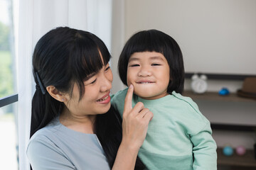 Happy Mom carry son in the house. Mother holding little boy walking around living room at home happy family moment.