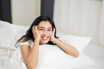 Obraz na płótnie Canvas Young woman wake up before lying asleep enjoying healthy in the morning. Beautiful asian woman sleeping well in comfortable cozy fresh bed on soft pillow white linen.