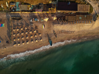 Aerial view of amazing beach with umbrellas and turquoise sea at sunrise. Black Sea at Vama Veche, Romania