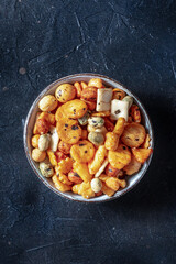 Japanese rice crackers in a bowl on a black slate background, shot from above with a place for text