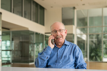 Fototapeta premium Portrait of senior businessman sitting at office and using phone