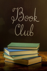 Book Club, toned image. A stack of books with chalk lettering on a blackboard