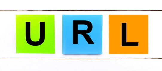 On a white wooden background there are three colorful bright stickers with text URL Uniform Resource Locator.