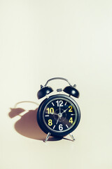 Black alarm clock with dial on beige background. Concept of time and timing with space for copying. Background.