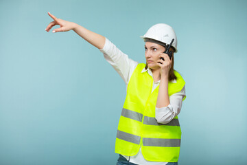 Professional engineer. A woman in a protective helmet and a bright vest gives instructions on a...
