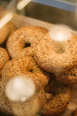 Fresh bagels with sesame on the glass showcase of the cafe.