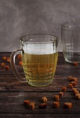 light beer in a glass mug with crackers on a dark background