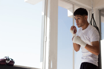 young latin boxer training by throwing punches in the air inside a gym with discipline and...