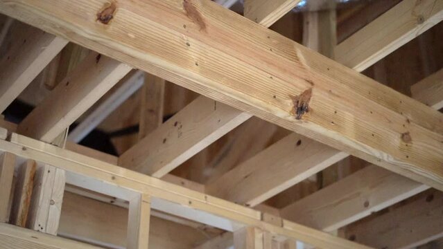 Home construction site showing rafters, framing, insulation and duct work in the ceiling