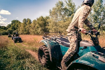 Quady w terenie , jazda czterokołowymi motorami w grupie na obozie survivalowym po bezdrożach z przewodnikiem, instruktorem wojskowym - obrazy, fototapety, plakaty