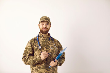 Fototapeta premium Studio portrait of happy army doctor. Man with ginger beard wearing camouflage uniform with stethoscope holding clipboard, looking at camera and smiling. Medicine, healthcare, military service concept