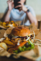 Enfoque selectivo en una hamburguesa completa con una persona desenfocada detrás 