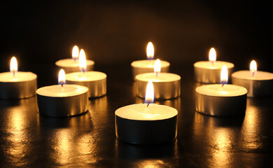 pointLots of candles on a wooden tablefocusspot specifically in on a black background.