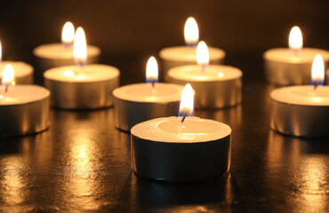 pointLots of candles on a wooden tablefocusspot specifically in on a black background.