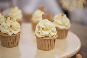 Tasty cupcakes on wooden board. Decorating a white cake with cream from the pastry bag.