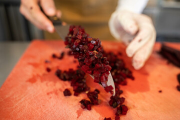 Close-up kitchen knife with freshly cut beets by chef. 