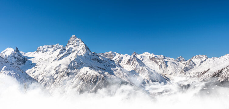 Panoramic view of winter snowy mountains in Caucasus region in Russia with blue sky