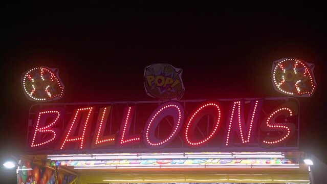 Balloons sign at night at carnival fair grounds.