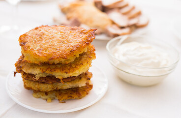 Potato pancakes with sour cream on white plate
