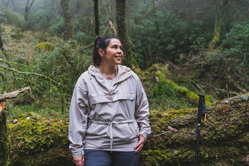 Chica joven guapa descansando en un árbol en un bosque con niebla y tomándose selfies