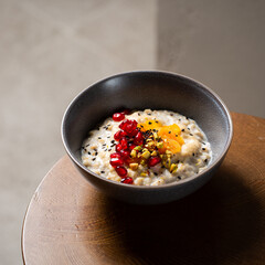 Healthy breakfast oatmeal porridge with sweet tahini, pistachio, dried apricots, pomegranate in bowl. Warm porridge oats, vegan vegetarian weight loss dieting breakfast food