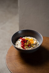 Healthy breakfast oatmeal porridge with sweet tahini, pistachio, dried apricots, pomegranate in bowl. Warm porridge oats, vegan vegetarian weight loss dieting breakfast food
