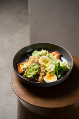 Plate with breakfast salads: avocado toast, egg, greens, fried cheese, quinoa