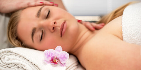 Obraz na płótnie Canvas Young woman lying on massage table receiving face massage. Beauty treatment concept.
