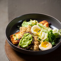 Plate with breakfast salads: avocado toast, egg, greens, fried cheese, quinoa