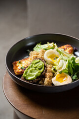 Plate with breakfast salads: avocado toast, egg, greens, fried cheese, quinoa