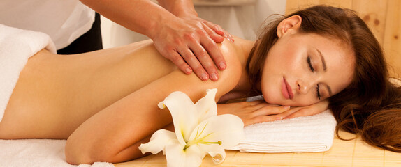 Body care. Spa body massage treatment. Woman having massage in the spa salon - banner size - 490337380