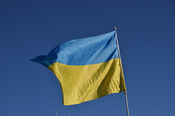 The national flag of Ukraine with a clear blue sky background.
